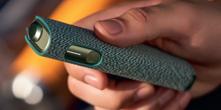 Hands holding smartphones and one IQOS device.