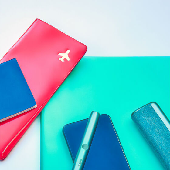 Travel documents, a mobile phone and an IQOS ILUMA PRIME Holder and Pocket Charger on a table.