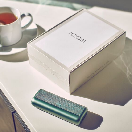 A woman looking at the back of an IQOS box.