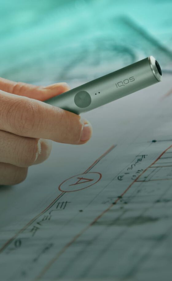 An IQOS ILUMA device in a person's hand.