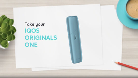 chargingIQOS ORIGINALS ONE heated tobacco device in turquoise next to cable charger.