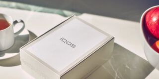 A person holding an unopened IQOS device box.