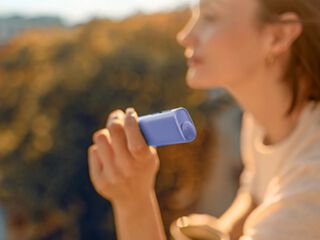A person holding an unopened IQOS device box.