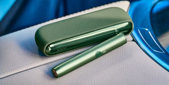 A person placing an IQOS ILUMA Pocket Charger into a charging station.